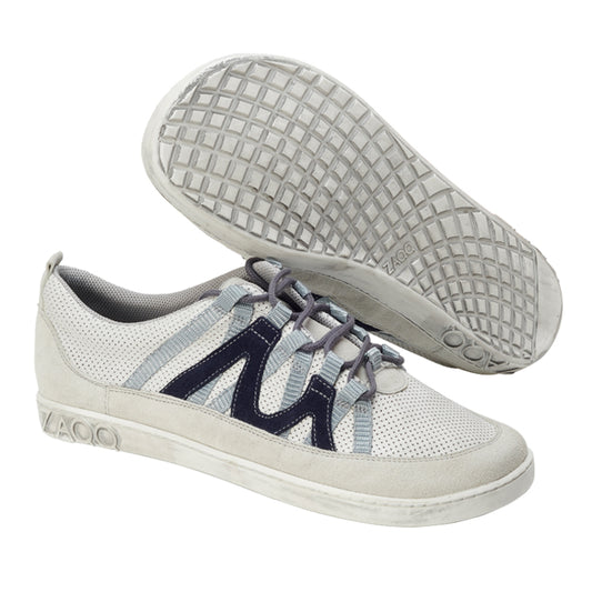 Ein Paar lässige ZAQQ DRAQE White Grey Sneaker mit strukturierter Sohle. Diese stylischen Schuhe haben marineblaue Akzente an den Seiten und hellgraue Schnürsenkel. Ein Schuh ist aufrecht abgebildet, während der andere das aufwendige Sohlenmuster zeigt, was ihr modisches Design unterstreicht.