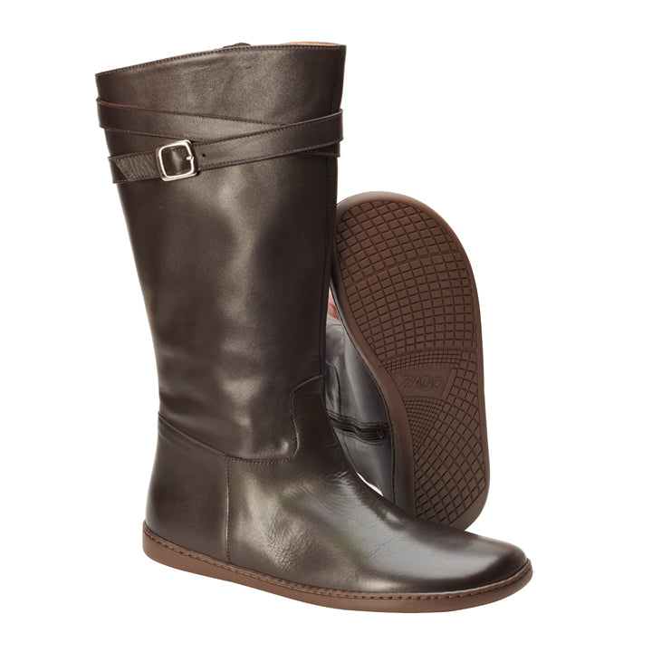 Die ATTRAQT Nappa Brown-Stiefel von ZAQQ sind hohe Damenstiefel aus edlem braunem Leder mit einem dekorativen Schnallenriemen oben. Ein Stiefel steht aufrecht, während der andere geneigt ist und seine strukturierte Sohle zur Schau stellt. Diese Stiefel aus Ziegenleder zeichnen sich durch ein elegantes und glattes Finish aus.