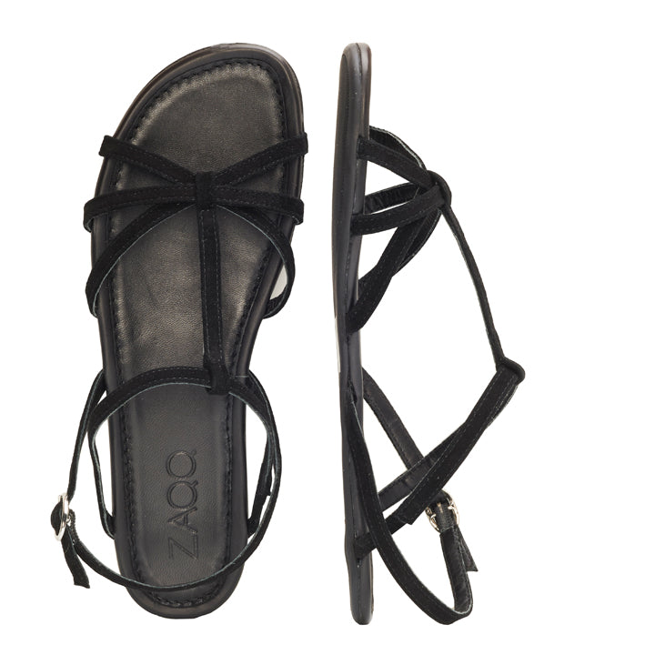 Ein Paar modische schwarze Riemchensandalen QADA von ZAQQ. Eine Sandale ist von oben zu sehen, sodass das Fußbett und die Velourslederriemen sichtbar sind, während die andere von der Seite zu sehen ist, sodass Schnalle und Sohle hervorgehoben werden.