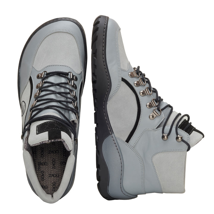 Ein Paar TREQ Grey Waterproof Wanderschuhe von ZAQQ, abgebildet in Seiten- und Draufsicht. Sie haben schwarze Sohlen, Schnürsenkel und metallische Ösen mit einem gemusterten Design auf dem Innenfutter. Diese strapazierfähigen Outdoorschuhe sind auf einem weißen Hintergrund zu sehen.