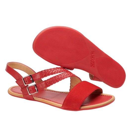 Wir präsentieren die BROOQE Red von ZAQQ, ein Paar elegante Barfuß-Sandalen aus Veloursleder. Diese Sandalen verfügen über Schnallenriemen und aufwendige Flechtdetails. Eine Sandale liegt auf der Seite und betont das Sohlendesign für optimalen Tragekomfort, während die andere aufrecht steht und das stilvolle Design des Oberteils und des Knöchelriemens zur Schau stellt.