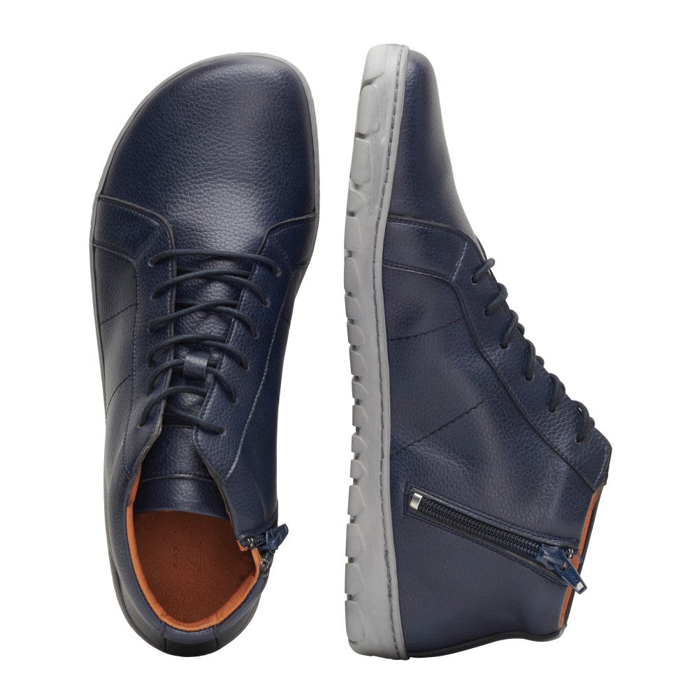 Wir präsentieren die QORE Mid Vegan Navy-Sneaker von ZAQQ mit einem eleganten, marineblauen Leder außen und einer grauen, flexiblen Sohle. Das Design zeigt einen Schuh von oben und den anderen von der Seite, wodurch ein stilvolles Reißverschlussdetail hervorgehoben wird. Innen verleiht ein orangefarbenes Futter diesem bequemen Stil eine lebendige Note.