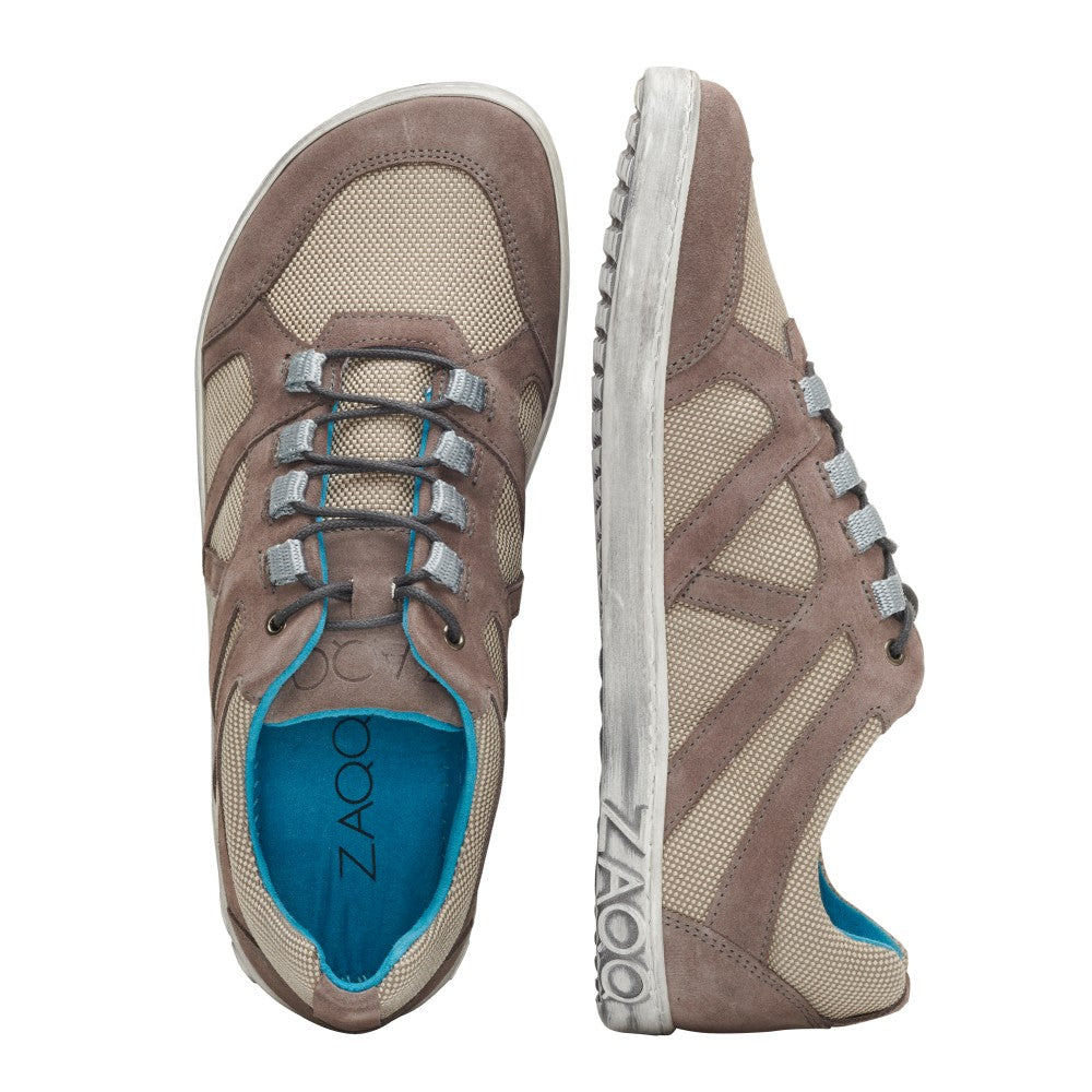 Die QUSQO Taupe Freizeitschuhe von ZAQQ zeichnen sich durch ein Design mit beigefarbenem, atmungsaktivem Netzgewebe, Akzenten aus taupefarbenem Wildleder, grauen Schnürsenkeln und einer blauen Innensohle aus. Das ZAQQ-Branding ist sowohl auf der Sohle als auch auf der Innensohle sichtbar. Ein Schuh wird aufrecht präsentiert, während der andere auf der Seite liegt und Bewegungsfreiheit für ultimativen Komfort bietet.