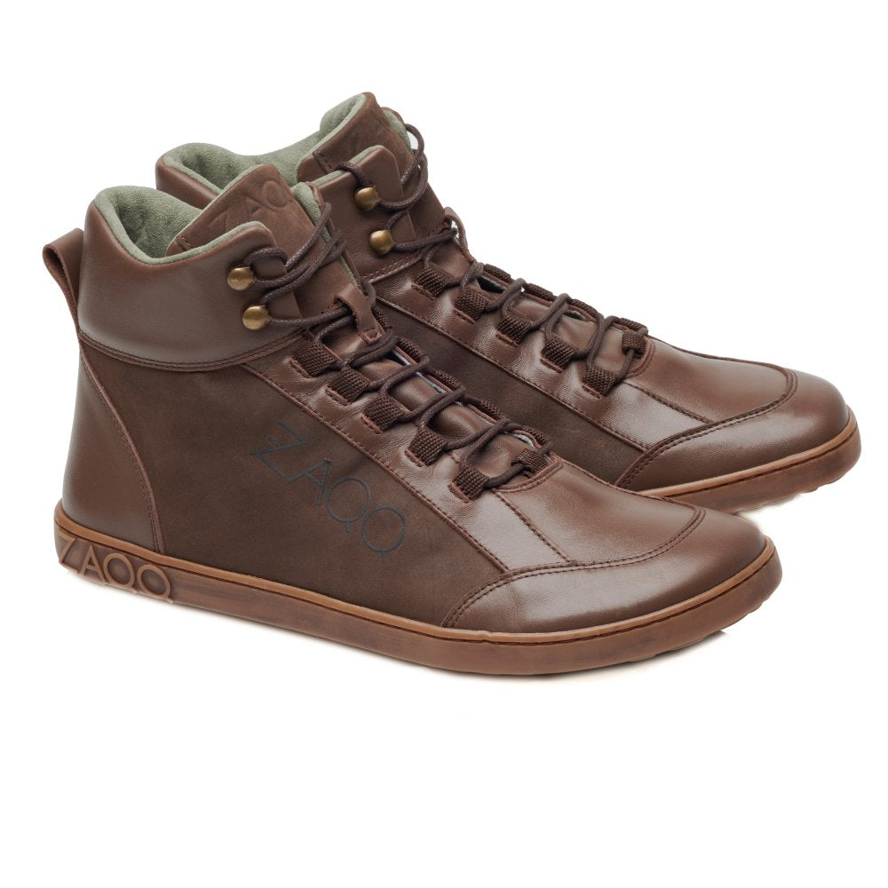 Die WALQER Brown Sneaker von ZAQQ sind braune High-Top-Schuhe mit glatter Oberfläche und Schnürdesign, die bemerkenswerte Bewegungsfreiheit bieten. Diese Schuhe im Barfuß-Boot-Stil verfügen über ein dezentes Logo, einen leicht erhöhten Knöchelkragen und ein weich aussehendes Innenfutter auf weißem Hintergrund.