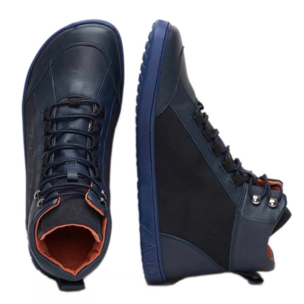 Entdecken Sie den WALQER Navy von ZAQQ, ein Paar stylische High-Top-Sneaker aus hochwertigem Nappaleder. Der linke Schuh ist von oben zu sehen und zeigt seine schwarzen Schnürsenkel, während der rechte Schuh aufrecht steht und die Seitenansicht zeigt. Beide Schuhe verfügen über flexible Sohlen, eine orangefarbene Innenseite und eine strukturierte Basis.