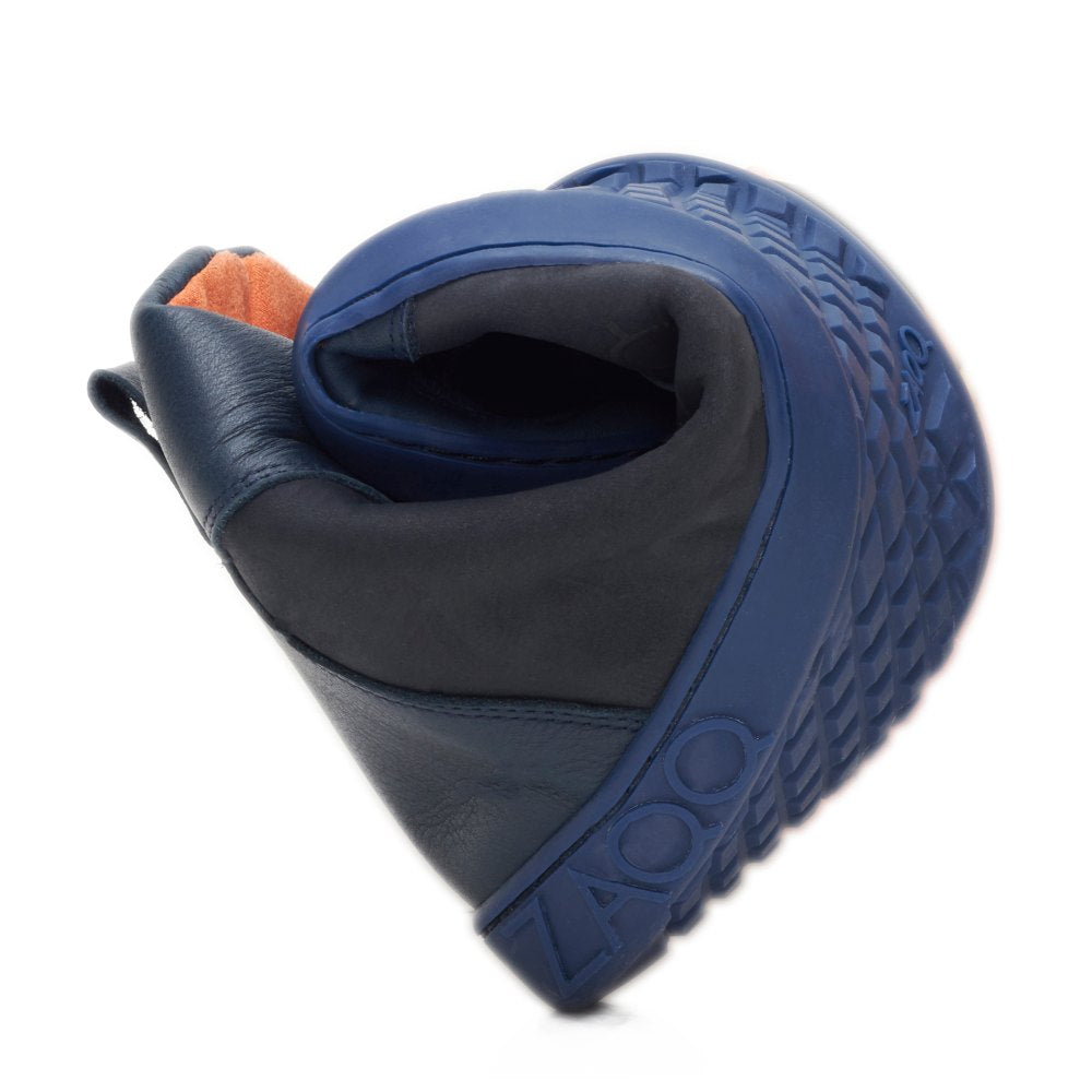 Der WALQER Navy von ZAQQ ist ein flexibler Schuh in Blau mit einer strukturierten Sohle, die seine Biegsamkeit beim Biegen hervorhebt. Dieser Barfußboot aus hochwertigem Nappaleder verfügt über kontrastierende schwarze und orangefarbene Elemente, die sein einzigartiges und stilvolles Design unterstreichen.