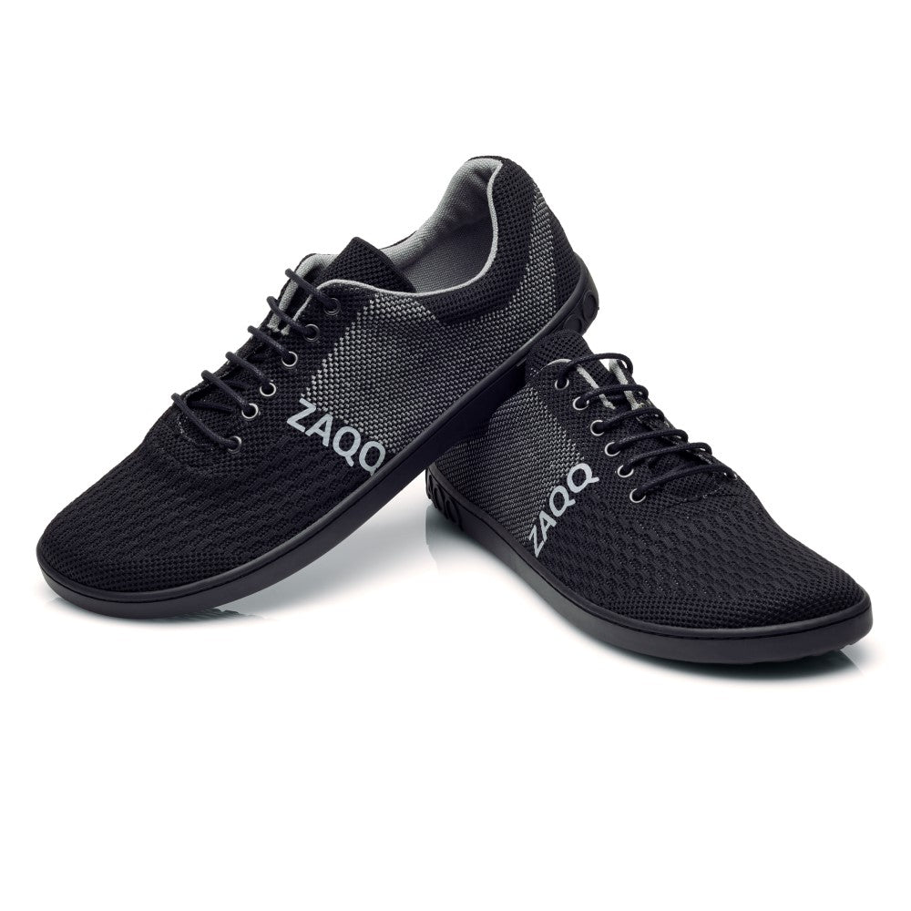 Der QNIT Black, ein Paar schwarze Sportschuhe von ZAQQ, zeichnet sich durch ein schlankes und leichtes Design mit einem atmungsaktiven Mesh-Obermaterial und Schnürsenkeln vor einem weißen Hintergrund aus.