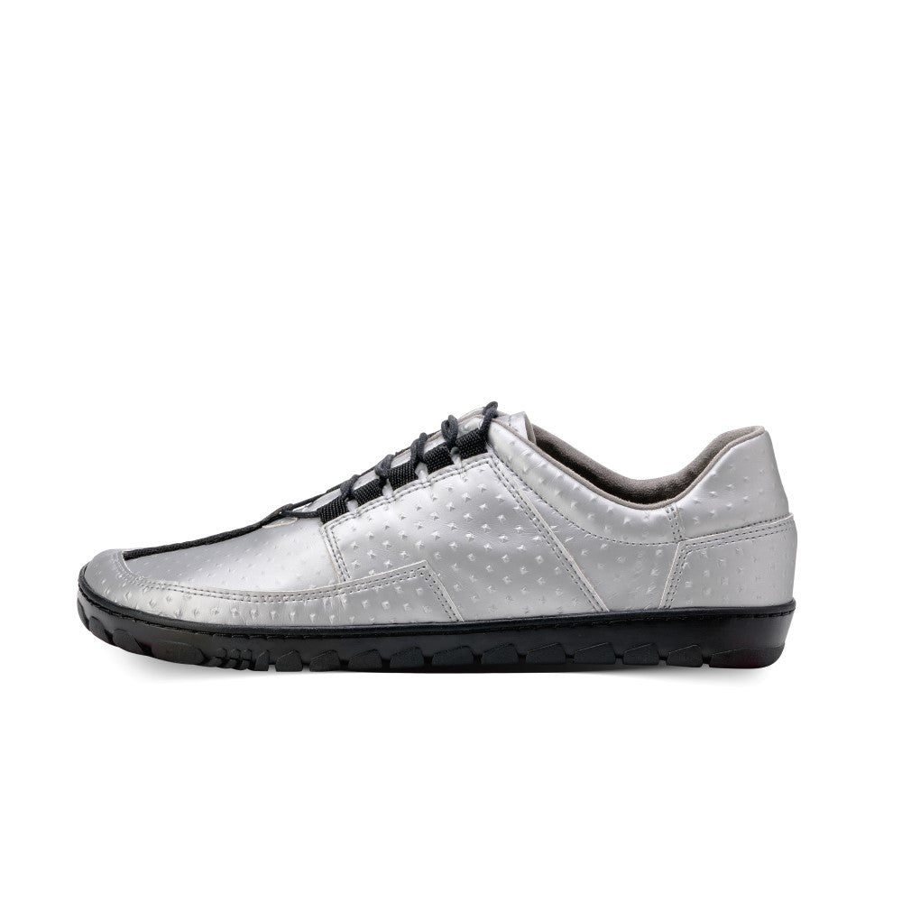 Wir präsentieren den JAQ Silver von ZAQQ: einen stylischen veganen Barfuß-Sneaker in Silber mit strukturierter Oberfläche und schwarzer flexibler Gummisohle. Dieses elegante Schnürdesign ist im Profil positioniert, um seine zeitgenössische und sportliche Ästhetik hervorzuheben.